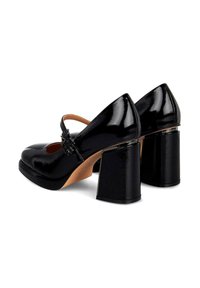 Zapatos de tacón de charol negro con tacón cuadrado, correa en el empeine, puntera afilada y acabado brillante. Detallados con un acento decorativo.