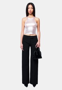 Schwarze hoch taillierte Hose, silbernes metallisches ärmelloses Oberteil und eine kleine schwarze Handtasche mit Krokodilprägung und silberner Hardware.