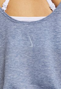 Light blue, ribbed tank top made of soft fabric, featuring a white Nike logo on the chest, and adjustable white straps on the back.
