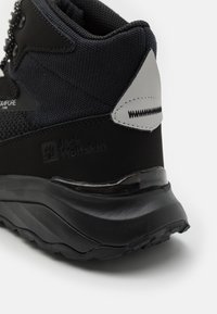 Schwarzer Wanderschuh mit strukturiertem Obermaterial aus Mesh, gummierter Sohle und einem silbernen Akzent an der Ferse. Das "Jack Wolfskin"-Logo ist geprägt.