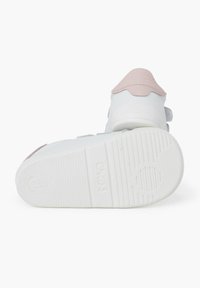 Sneaker bianche con un accento rosa sul tallone e sulla linguetta, dotate di una suola testurizzata e di un cinturino in Velcro. Taglia 21 indicata sulla suola.