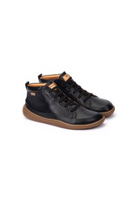 Zapatos de cuero negro de media altura con puntera redonda, cordones en la parte delantera, detalles en color beige y suela de goma. Detalles perforados cerca de la zona de los dedos.