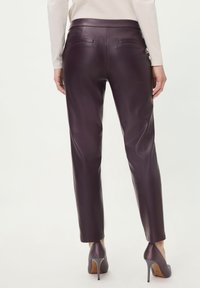 Burgundy leather pants with a fitted design, featuring two back pockets and a smooth texture, paired with matching high-heeled shoes.