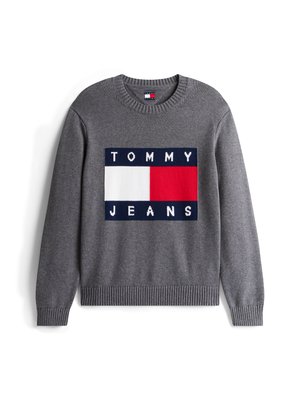 Sivi pleteni džemper središnjim logotipom na kojem stoji "TOMMY" i "JEANS" u bijeloj i tamnoplavoj boji, s crveno-bijelim prugastim pravokutnim akcentom.