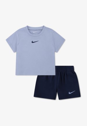 Camiseta de manga corta color azul claro de Nike y pantalones cortos con cintura elástica azul marino con logotipos de Nike en el pecho y la pierna, colocados sobre un fondo blanco.