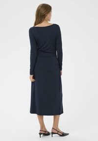 Marineblaues Langarmkleid mit Rundrücken, aus weichem Material gefertigt, mit einer taillierten Taille und einem geraden Rock, der bis zur Mitte der Wade reicht.