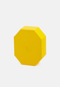 Prodotto ottagonale di colore giallo realizzato in materiale testurizzato, con un logo leggermente in rilievo e bordi piatti. Superficie liscia con una finitura opaca.