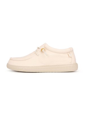Beige lage mocassinstijl casual schoen met rubberen zool en zijtouwdetail op een witte achtergrond.