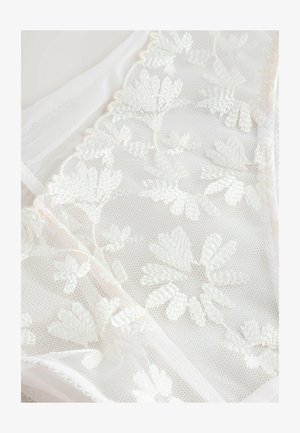 Balts mežģīņu audums ar ziedu izšuvumu, maiga tekstūra un caurspīdīgs materiāls ar vieglu spīdumu. Malas apgrieztas ar mīkstiem viļņiem.