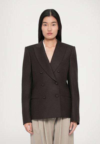 Bruine dubbelgeknoopte blazer met pieklapels, twee voorknoopzakken en zes knopen. Soepele textuur met gestructureerde pasvorm. Op maat gemaakte ontwerp.