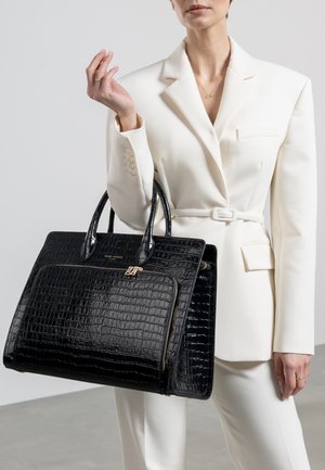 Sac à main en cuir embossé crocodile noir avec une forme structurée, des poignées doubles et une poche zippée à l'avant. Caractéristiques des accents en métal doré.