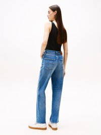 Lichtblauwe denim jeans met een relaxte pasvorm, voorzien van achterzakken en een bruine leren tailleband detail. Geschikt met witte sneakers.