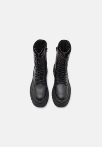 Black lace-up boots featuring a textured leather upper, a sturdy rubber sole, and a side zipper for easy wear.