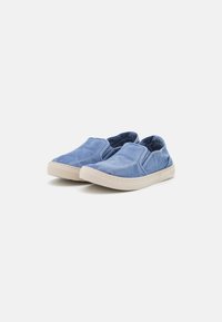 Plave slip-on cipele izrađene od mekog tekstila s glatkom teksturom. Imaju svijetlu gumenu potplate i elastične bočne akcentne detalje za lakše oblačenje.