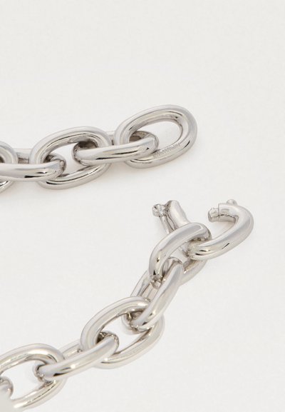 Lähedalt vaatlus sillerdavate hõbedaste ketilinkide ja kinnituse mehhanismiga helel taustal.