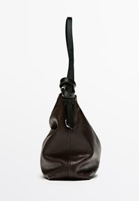 Borsa in pelle marrone scuro con un design morbido, dotata di una tracolla nera regolabile e una superficie liscia. Include un dettaglio in metallo di tonalità argentata.