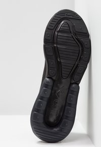 Semelle de chaussure de sport noire avec caoutchouc texturé, présentant des rainures à motif et des accents rectangulaires en relief. Affiche la marque "Air Max".