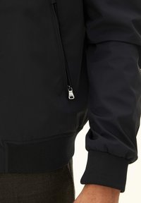 Sort bomberjakke med en glat, blank finish. Har en lynlås lomme og ribbede manchetter for et tætsiddende look. Slankt design, moderne æstetik.