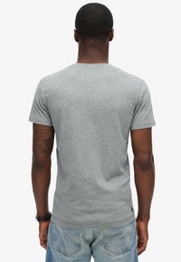 Lys grå kortærmet t-shirt lavet af tekstureret stof. Har rund hals og almindelig pasform. Bagsiden viser en glat overflade og syninger.