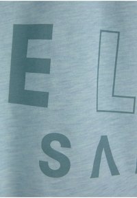 Helles blauen Baumwoll-T-Shirt mit großen dunkelgrünen Blockbuchstaben und geometrischen Designelementen, mit einer weichen, strukturierten Oberfläche.