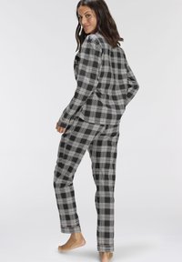 Black and gray plaid pajama set featuring long sleeves and pants with a relaxed fit. Soft fabric with contrasting stitching details.