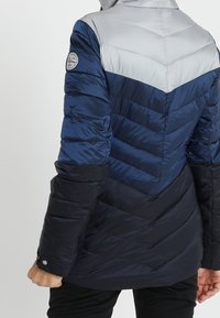 Gep padded Jacke in drei Farbtönen: Hellgrau, Marineblau und Dunkelmarine. Verfügt über ein Chevron-Design, eine elegante Optik und Druckknopf-Akzente.