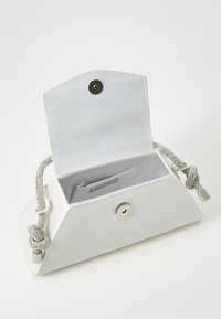 Borsa a pochette in pelle bianca con design pieghevole, manico a catena argentata e chiusura a scatto. L'interno presenta uno slot per carte e una foderatura liscia.