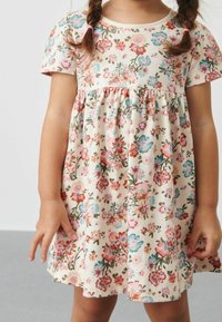 Robe fleurie à manches courtes, avec une base crème et un imprimé floral multicolore. Tissu en coton texturé avec taille froncée.