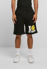 Svarte bomullsshorts med avslappet passform, med et hvitt og gult grafisk trykk som står "I ❤️ MY HATERS" på venstre ben.