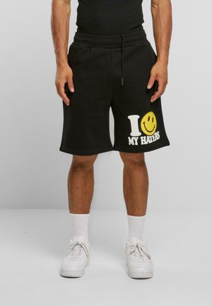 Svarte bomullsshorts med avslappet passform, med et hvitt og gult grafisk trykk som står "I ❤️ MY HATERS" på venstre ben.