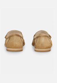 Beige Suede Slipper mit runder Zehenpartie, flacher Sohle und leicht erhöhtem Schaft. Minimalistisches Design mit glatter Textur und ohne sichtbare Beschläge.