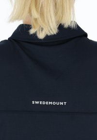 Maglietta sportiva blu navy con tessuto testurizzato e colletto, dotata di un logo bianco "SWEDEMOUNT" vicino all'collo.