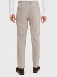 Jasno beżowe spodnie wykonane z teksturowanej tkaniny, z delikatnym wzorem w kratę, dwiema tylnymi kieszeniami z guzikami oraz dopasowanym krojem.