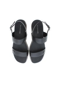 Svarta lädersandaler med två breda remmar och en rem vid vristen, med en silverfärgad emblem på sidan. Slät yta, öppen tå-design.