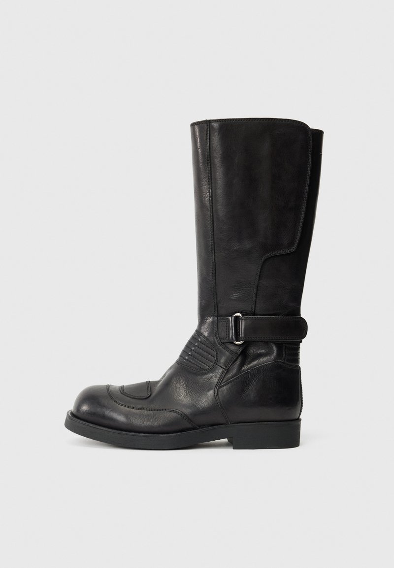 Bottes noires en cuir, montant jusqu'au genou, avec un bout arrondi, des coutures contrastantes, des détails de boucle sur le côté et des accents texturés sur l'extérieur.