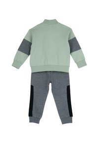 Mintgrön sweatshirt med grå detaljer, ribbade ärmslut och hög krage, tillsammans med grå joggers med svarta sidostråk och textilåterverk.