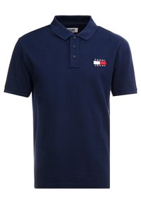 Námořnická polo košile z bavlny, s límečkem, třemi knoflíky, krátkými rukávy a malou nášivkou loga v červené, bílé a modré barvě.