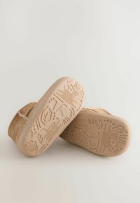 Braune Wildlederstiefel mit einer beigen Gummisohle, die ein strukturiertes, gemustertes Profil-Design aufweist. Weiches Obermaterial mit runder Zehenpartie und genähten Details.