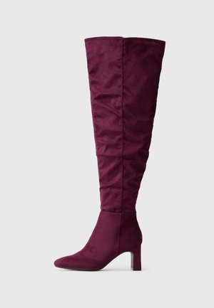 Botte haute pour femme en daim violet profond avec un talon bloc de hauteur moyenne et un design de tige légèrement décontracté.