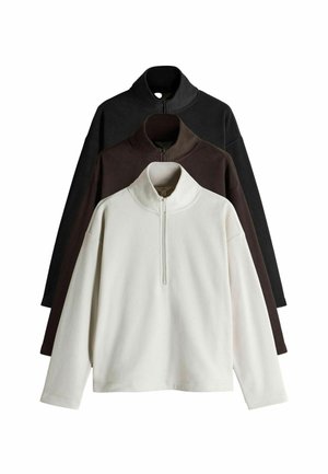 Drie fleece sweaters in het wit, bruin en zwart, met een rits kraag, lange mouwen en een relaxte pasvorm. Zachte textuur overal.
