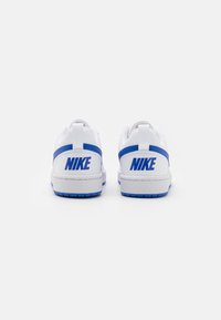 White sneakers featuring a blue accent stripe and "NIKE" logo on the heel. Textured rubber sole with a clean, smooth design.
