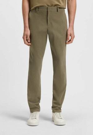 Olive green tailored trousers with a subtle textured pattern, featuring a standard waistband and front pockets, paired with white sneakers.