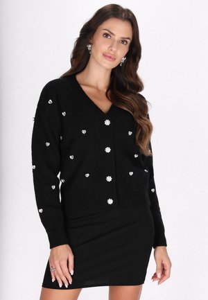 Cardigan nero realizzato in morbido materiale, con scollatura a V, chiusura con bottoni e decorazioni a forma di cuori e fiori.