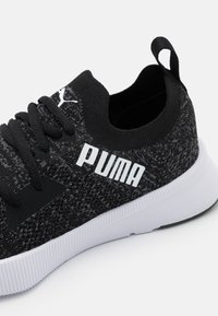 Botte de sport en maille noire avec logo Puma blanc, tige texturée, lacets noirs plats et semelle extérieure en caoutchouc blanc. Talon arrondi et col en forme de chaussette.