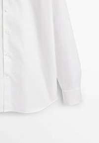 Witte langemouwen overhemd met knopen, voorzien van een rechte kraag en manchet mouwen, gepresenteerd tegen een effen witte achtergrond.