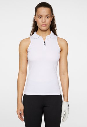 White sleeveless polo shirt with a zippered collar, featuring a subtle logo detail. Smooth fabric, fitted design, paired with black pants and a glove.