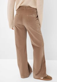 Bruine corduroy broek met brede pijpen en een gladde textuur, voorzien van twee achterzakken en een subtiele merketiket op de tailleband.