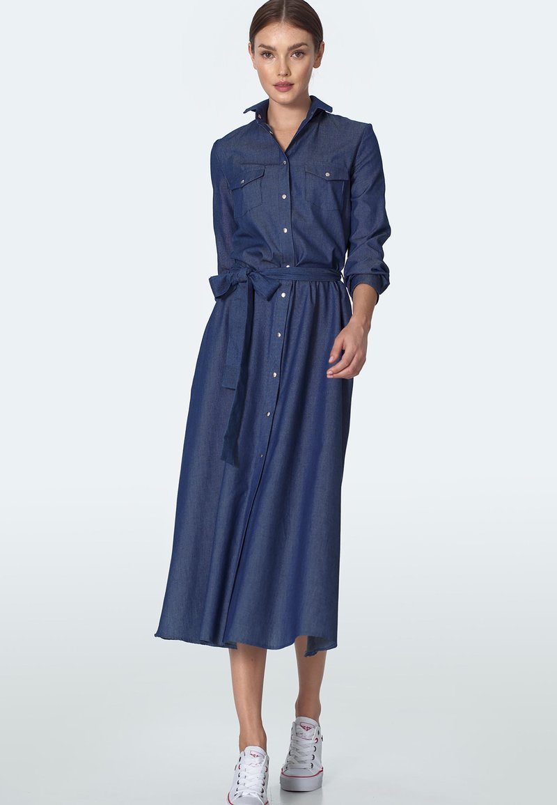Sukienka koszulowa z denimu z długimi rękawami, zapinana na guziki z przodu, z dwiema kieszeniami na piersi i odpinanym paskiem. Posiada zwiewny spódnicę midi. Kolor: ciemnoniebieski.