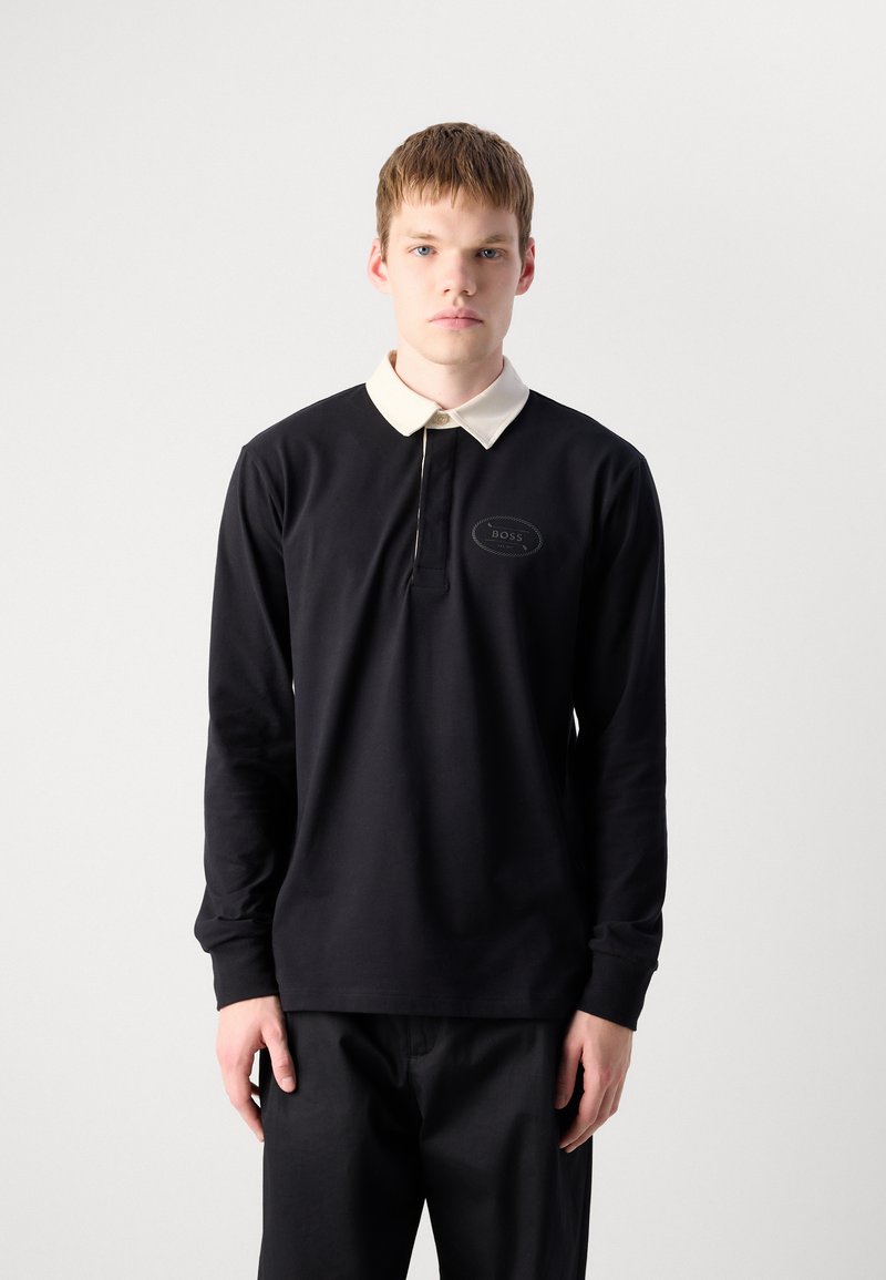 Zwarte long sleeve polo shirt met een crèmekleurige kraag, voorzien van een voorste sluiting en een rond logo detail op de linkerborst.