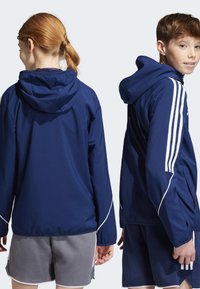 Marineblaues Kapuzenshirt mit weißen Akzenten, ausgestattet mit einer Reißverschlusstasche, geradem Schnitt und drei weißen Streifen an den Ärmeln.